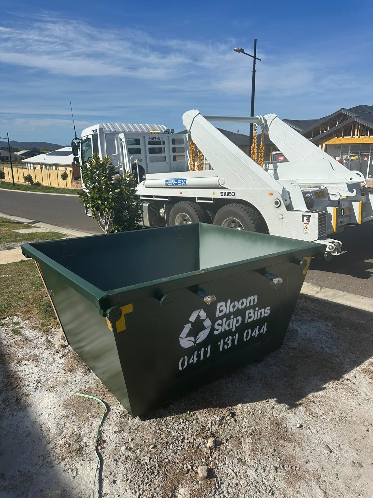 Bloom 2m³ mini skip sitting on a concrete driveway in front of a Melbourne home, with room to spare either side