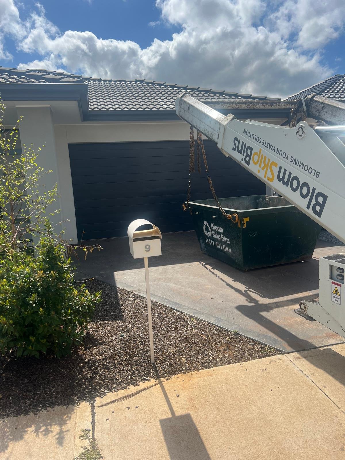 Bloom skip bin on a driveway with its walk-in door open